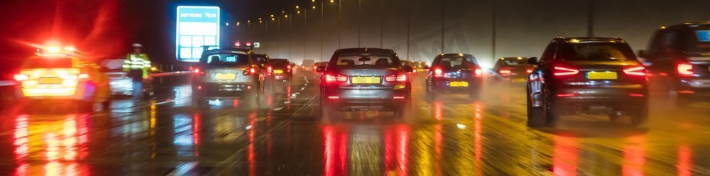 全景网横幅运动模糊交通的照片在晚上在雨在一条英国高速公路有警察和汽车