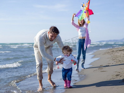 秋天，一家人带着小女儿在海滩上休息，玩风筝。幸福的一家人在秋日享受矢量