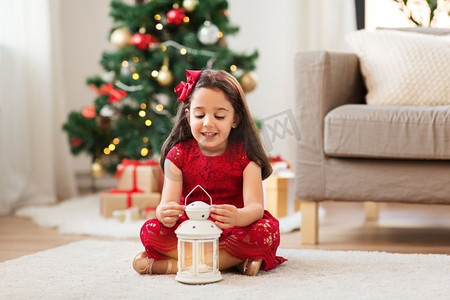 圣诞节、节日和童年的概念--家里提着灯笼的小女孩。圣诞节家里提着灯笼的小女孩