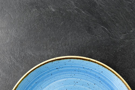 餐桌摆设、餐具和餐饮理念-板岩背景下蓝色陶瓷板的特写。板岩背景上的蓝色陶瓷板特写