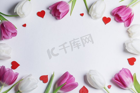 鲜艳的郁金香花框和白色背景上孤立的装饰心形。郁金香和心形的框架