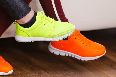 两个面目全非的女人穿着运动鞋，红色和霓虹灯绿色的。健身套装件..两双运动鞋