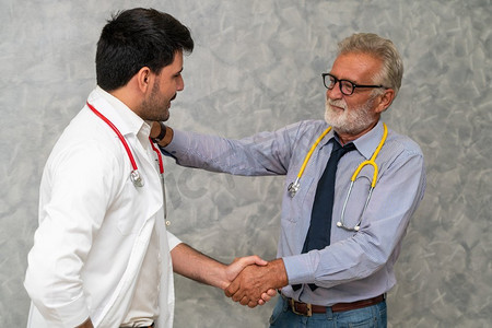 一名住院医生与另一名医生握手。医护人员团队精神和医护人员服务理念。