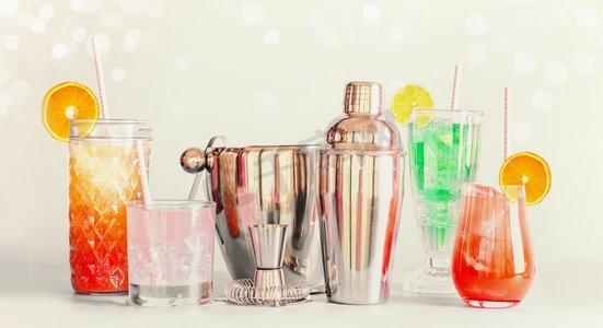 五颜六色的夏天长饮料酒吧和鸡尾酒工具在各种玻璃与饮用吸管和柑橘水果站在轻背景