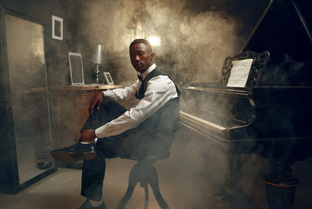 大黑人摄影照片_时尚的乌木大钢琴演奏家，爵士乐演奏俱乐部。黑人表演者在演奏旋律前摆姿势