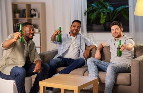 喝啤酒摄影照片_友谊、休闲和人的概念—快乐的男性朋友晚上在家喝啤酒。快乐的男性朋友喝啤酒在家里晚上