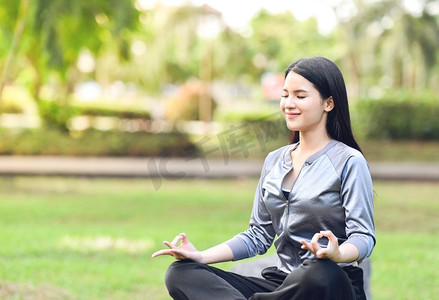 瑜伽妇女年轻的手做瑜伽和放松冥想在绿色草地在公园户外