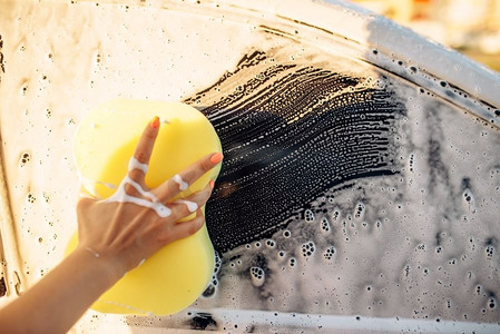回弹海绵摄影照片_女性用海绵手擦洗汽车用泡沫、洗车。年轻女子自助洗车。夏日户外洗车 