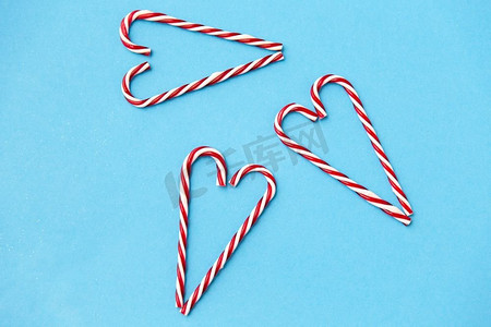 圣诞节和冬季假期概念—糖果手杖装饰在心的形状在蓝色背景。心形糖果手杖装饰品