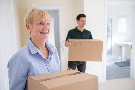 老年妇女在退休时削减规模携带箱子进入新家的搬家日与搬迁男子帮助