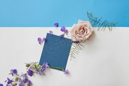 快乐的春天字母。蓝色的问候卡与空白和鲜花周围。俯视图，平面图。春天的花朵框架