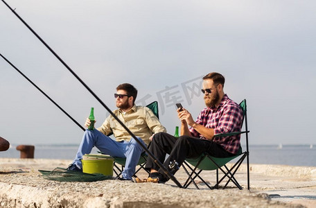 休闲和人的概念—男性朋友与智能手机钓鱼和喝啤酒。朋友与智能手机钓鱼和喝啤酒