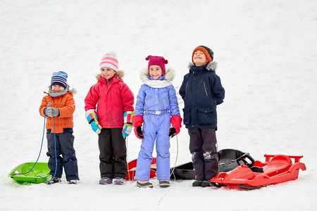 童年，雪橇和季节概念—一群快乐的小孩子在冬天雪橇。快乐的小孩子与雪橇在冬天