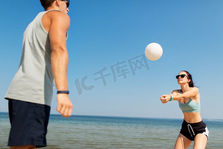 健身、运动和生活方式理念-夏季海滩上打排球的幸福情侣。夏日沙滩上打排球的幸福夫妻