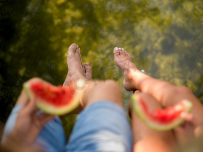 河岸摄影照片_夫妇在爱享受野餐时间吃西瓜在美丽的自然在河岸