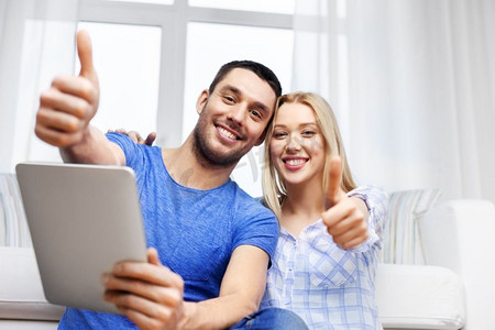 技术，互联网和人的概念—快乐的夫妇与平板电脑显示大拇指在家里。夫妇与平板电脑显示大拇指