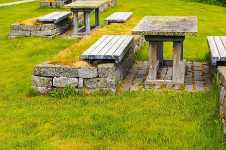 野餐桌摄影照片_挪威野餐地点表和长凳在绿色草甸领域，斯堪的纳维亚欧洲营地与野餐桌在挪威性质