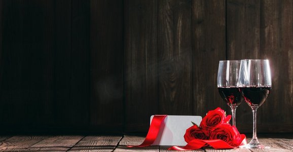 玫瑰和红酒摄影照片_情人节送两杯红酒、玫瑰和贺卡。葡萄酒、玫瑰和卡片情人节
