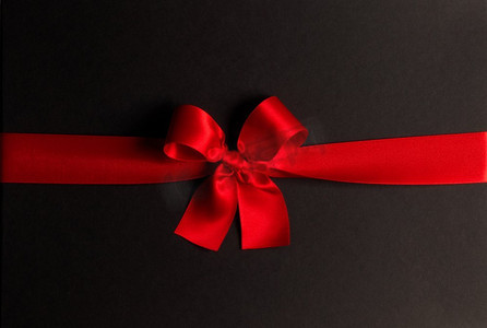 黑色背景上的红色礼物蝴蝶结。黑色上的红色礼物蝴蝶结