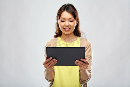 科技与人的概念-快乐的亚洲女性在灰色背景下使用平板电脑。快乐的亚洲女性使用平板电脑
