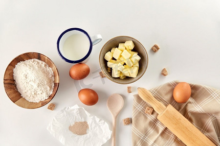 馒头摄影照片_烹饪食品和烹饪概念—餐桌上的滚轴、黄油、鸡蛋、面粉和蔗糖。馒头、黄油、鸡蛋、面粉、牛奶和糖