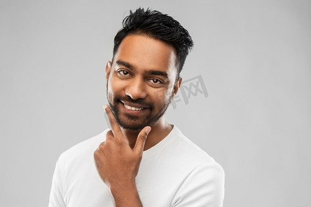 修饰和人概念—微笑的印度人触摸他的胡子在灰色背景微笑的印度男子触摸他的胡子