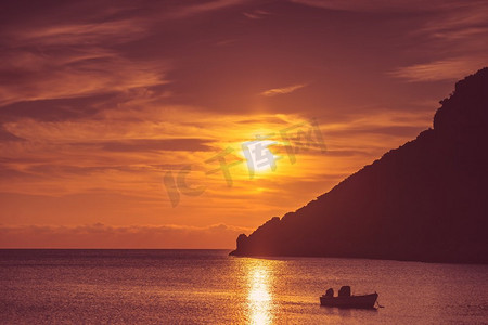 海面天空摄影照片_风景日出或日落在海面，船停泊在海湾，希腊。海面上的日出或日落