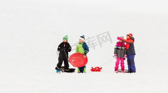 童年，雪橇和季节概念—一群快乐的小孩子在冬天雪橇。快乐的小孩子与雪橇在冬天