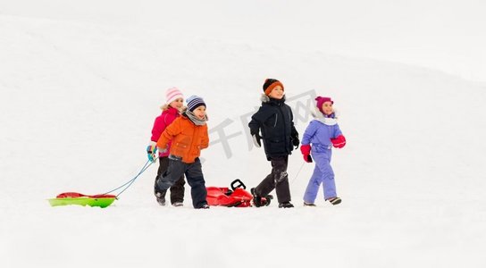 玩雪橇的孩子摄影照片_童年、雪橇和季节概念-一群快乐的小朋友在冬天拉雪橇。冬天玩雪橇的快乐小朋友