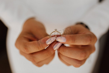 新娘手持镶有钻石的订婚戒指，美丽的指甲，前视，婚礼当天