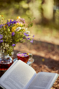 露天茶会。一个杯子和茶壶特写镜头在自然界在森林里。一束花和一本书