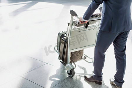 成熟商人推着行李车在机场办理登机手续