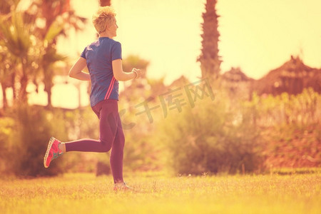 户外运动女摄影照片_年轻的运动女跑步者训练马拉松跑在美丽的热带公园在阳光明媚的早晨