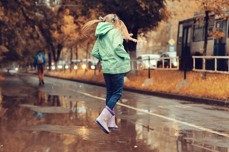 秋雨摄影照片_女孩在秋雨中跳进水坑