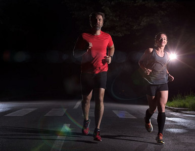 跑步队在夜间训练。一群健康的人在城市公园慢跑，跑步者团队在夜间训练