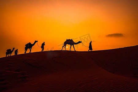 观光地摄影照片_骆驼人，日落时赶骆驼的人。印度拉贾斯坦邦贾萨尔梅尔日落时的沙漠。