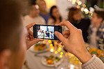 庆祝、节日和人们的概念--拿着智能手机在晚宴上拍全家福。一名男子在晚宴上与家人合影