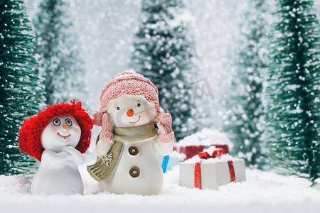 两个小可爱雪人朋友与礼物在森林下的雪。雪人和礼物