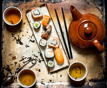 寿司和卷饼配上花草茶，背景是古老的乡村。寿司和卷配凉茶