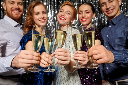圣诞节，庆祝和假日概念—快乐的朋友在聚会上碰杯香槟。朋友与香槟杯在圣诞派对