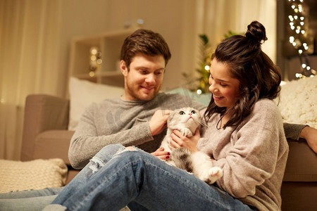 宠物，hygge和人的概念—快乐的夫妇与猫在家里。幸福的夫妇与猫在家里。快乐的夫妇与猫在家里