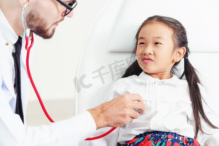 年轻的男医生在医院办公室检查小孩。孩子很高兴，不怕医生。儿童医疗保健概念。
