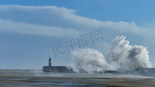 在纽黑文英国海岸线上的巨大风暴中，巨浪越过港口墙壁撞到灯塔上，惊人的图像显示了海洋的力量