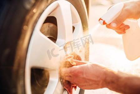 男性手用车边清洁器清洁磁盘，洗车。洗车站。男性手清洁盘与汽车轮辋清洁器