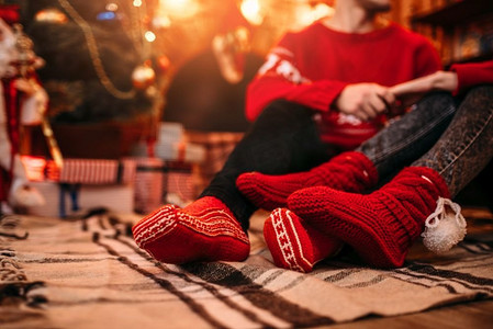 相爱的情侣幸福地在一起，圣诞假期。圣诞庆典，男人和女人坐在地板上，背景是装着礼物的盒子