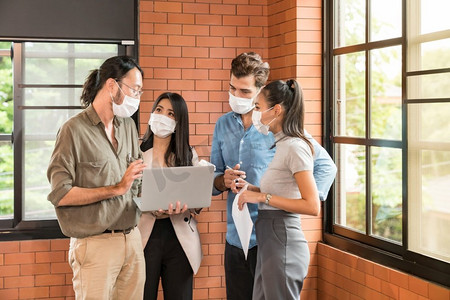 企业工作者团队会议和集思广益。他们在新常态办公室戴上防护口罩，防止冠状病毒新冠肺炎传播。