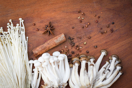 Enoki或金针蘑菇和Shimeji蘑菇与草药和香料在木背景 