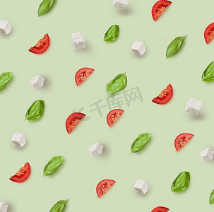 绿色背景的卡普雷斯沙拉的配料图案。马苏里拉奶酪、樱桃番茄和罗勒图案