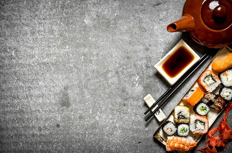 山葵摄影照片_面包卷和寿司，花草茶和酱油。在石桌上。面包卷、寿司和花草茶