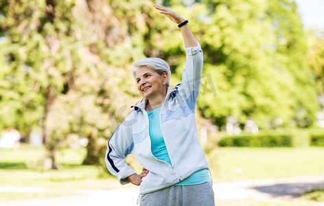 健身、运动、健康的生活方式理念--快乐微笑的老年女性在夏季公园锻炼。快乐老年女性在夏季公园锻炼